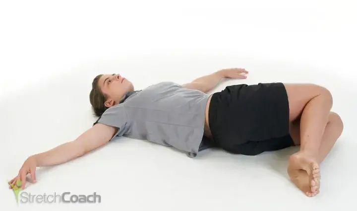 woman streching lower back by laying on the ground with legs bent